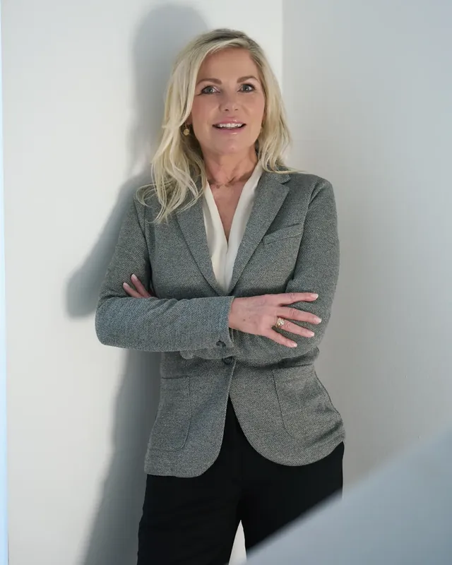 Ulrike von den Driesch, Coach für Führungskräfte, mit verschränkten Armen an einer hellen Wand
