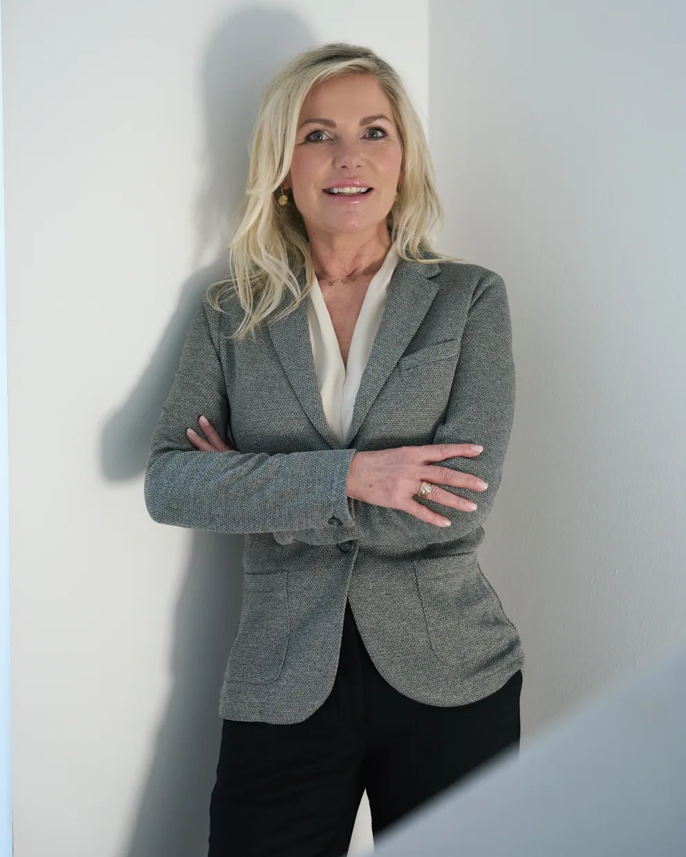 Ulrike von den Driesch, Coach für Führungskräfte in Köln, mit verschränkten Armen an einer hellen Wand