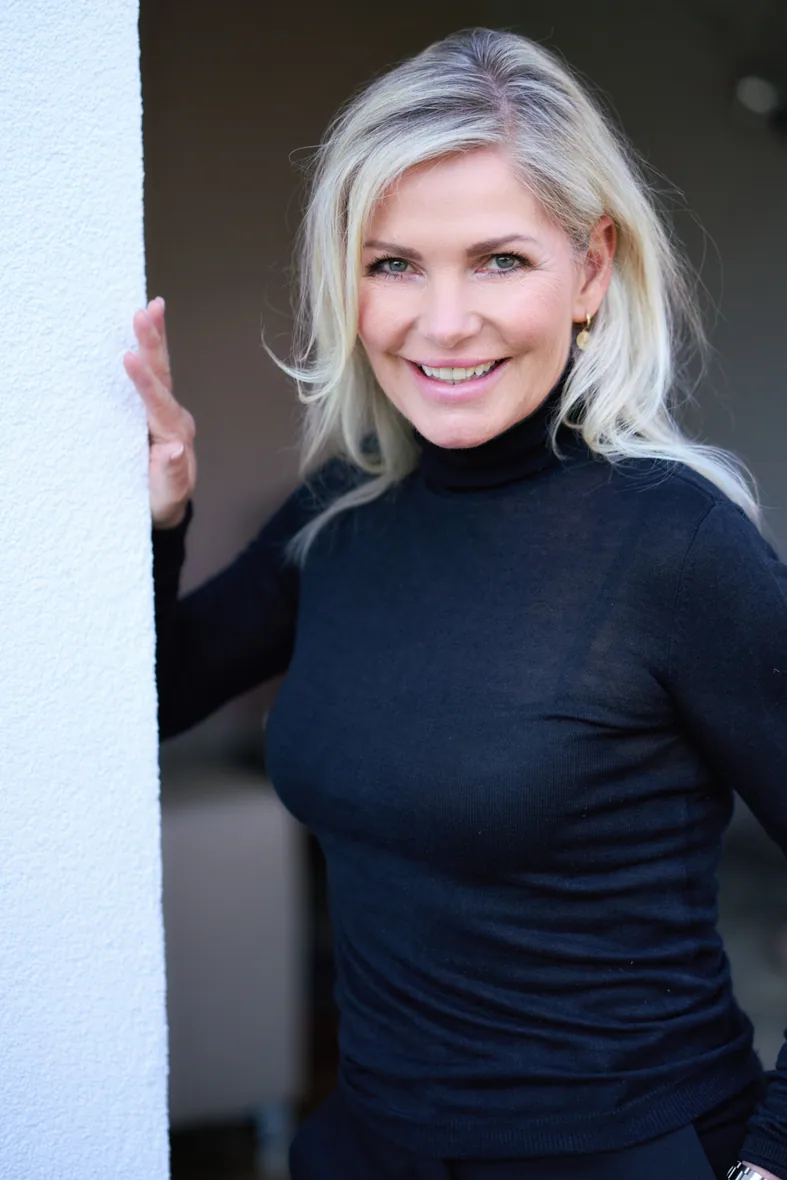 Ulrike von den Driesch, lächelnd an eine Wand gelehnt